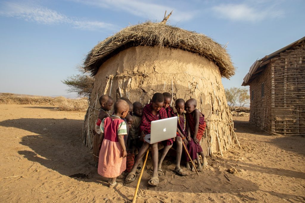 Afrikanische Kinder sitzen um ein Macbook herum.